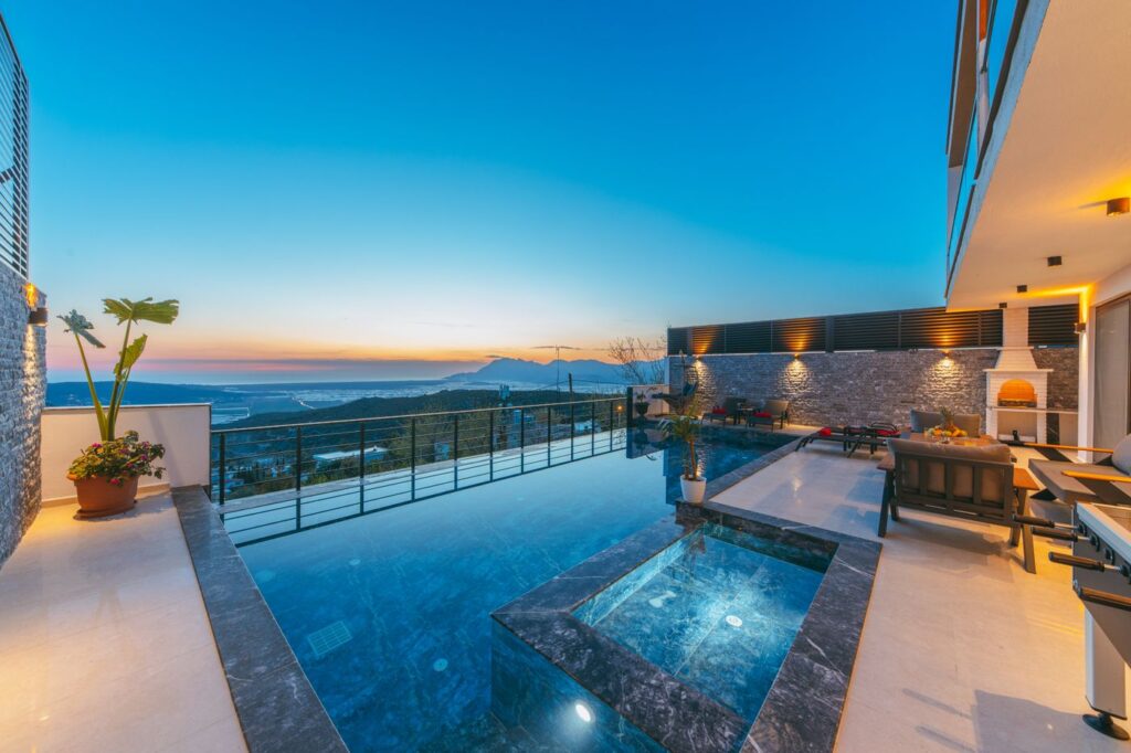 Infinity pool and terrace overlooking mountains at sunset